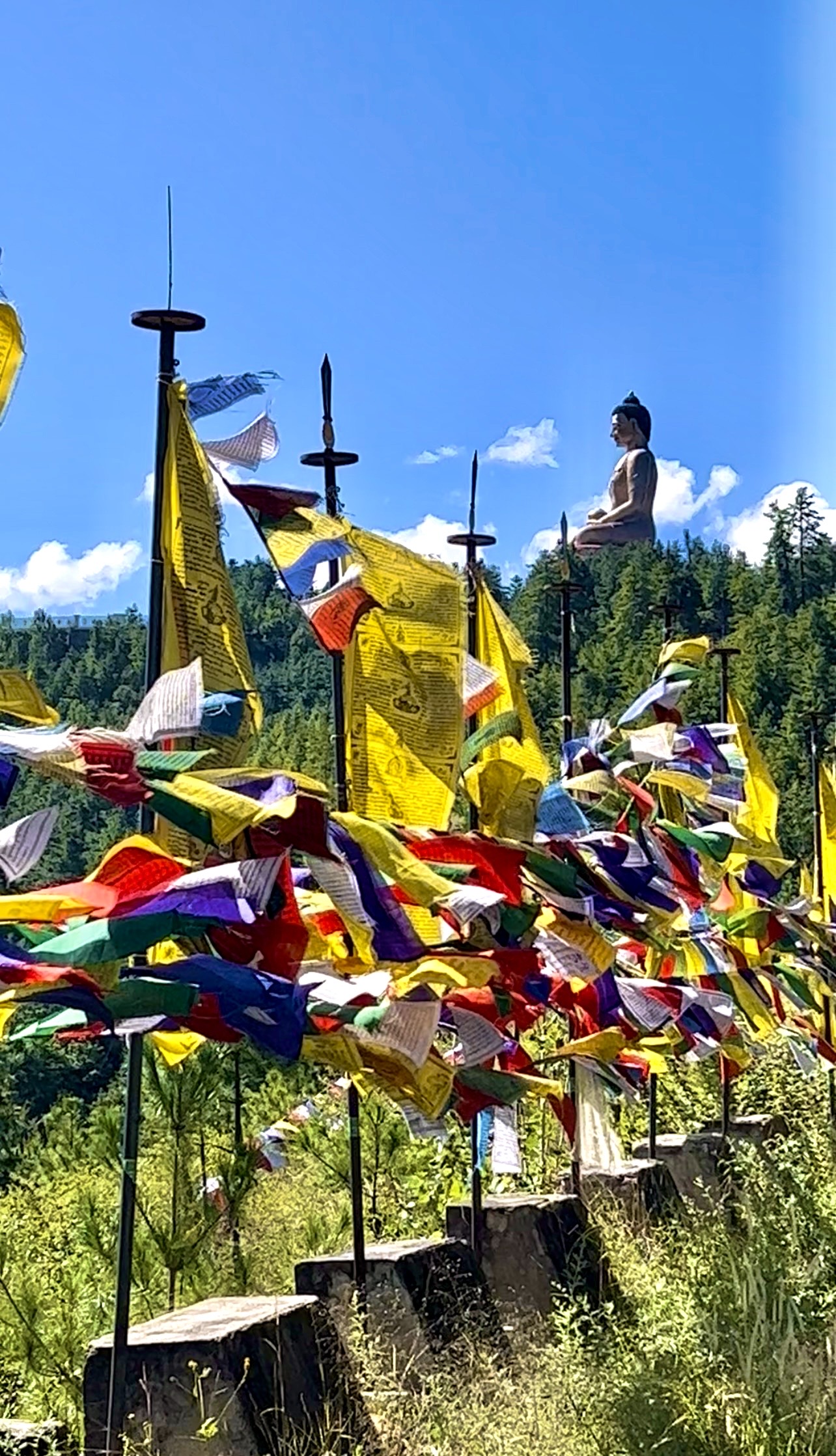 Estatua de Buda sobre un paisaje de montaña con banderas de oración